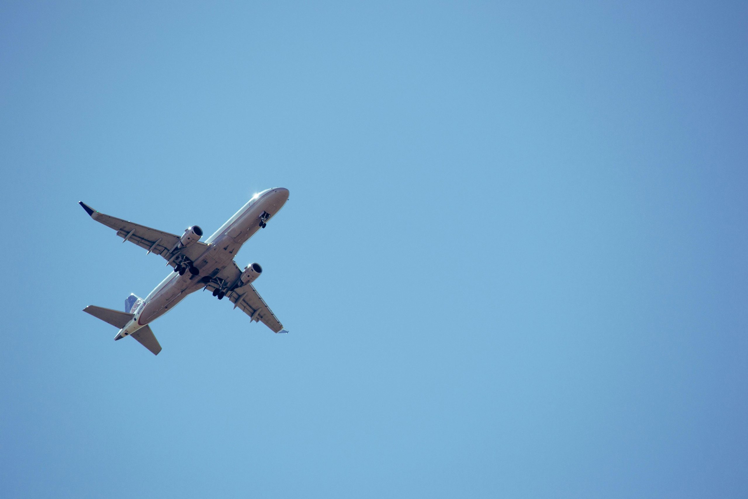 Home A commercial airplane captured mid-flight against a clear blue sky.