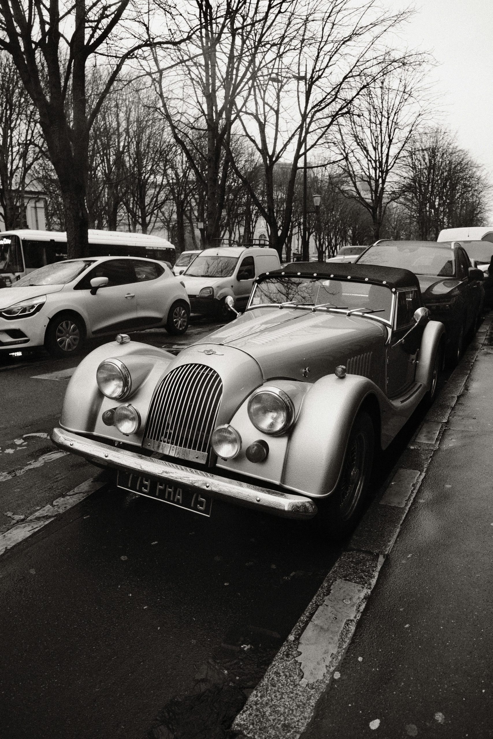 Classic Morgan car parked on a rainy city street, showcasing vintage elegance.